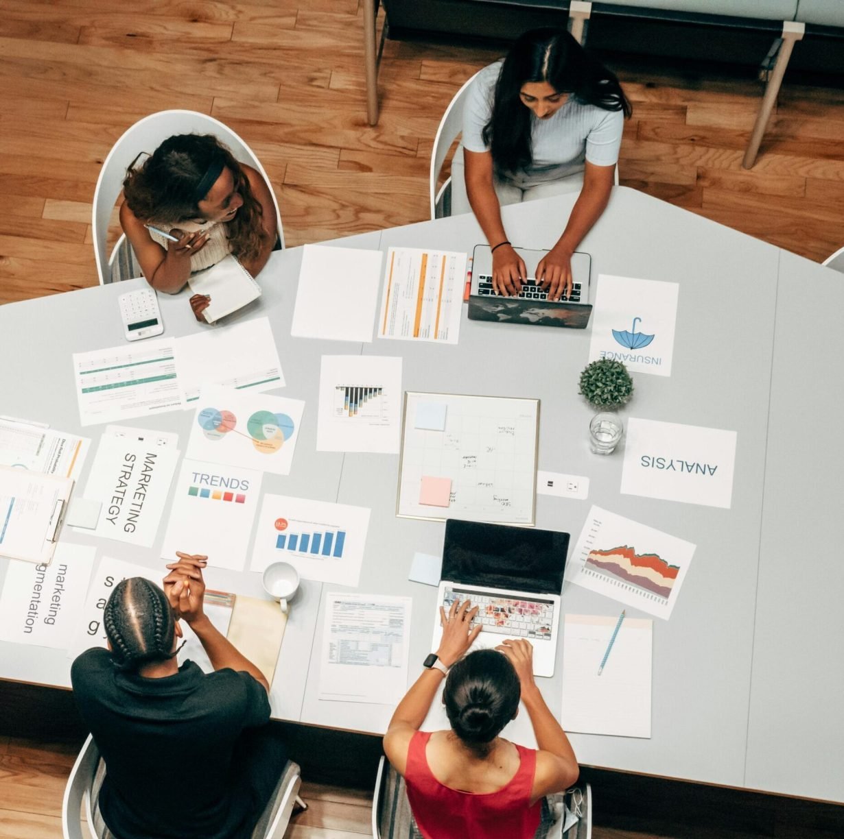 A diverse group working on marketing strategies with charts and laptops in an office setting.